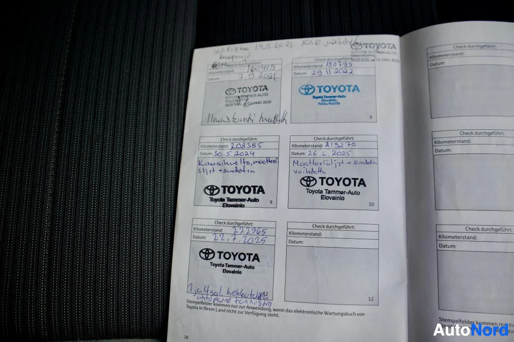 Yksityiskohta: Avatun huoltokirjan sivu, jossa näkyy Toyota Tammer-Auto Elovelnio -leimoja ja käsinkirjoitettuja huoltotietoja päivämäärineen ja kilometrilukemineen.
