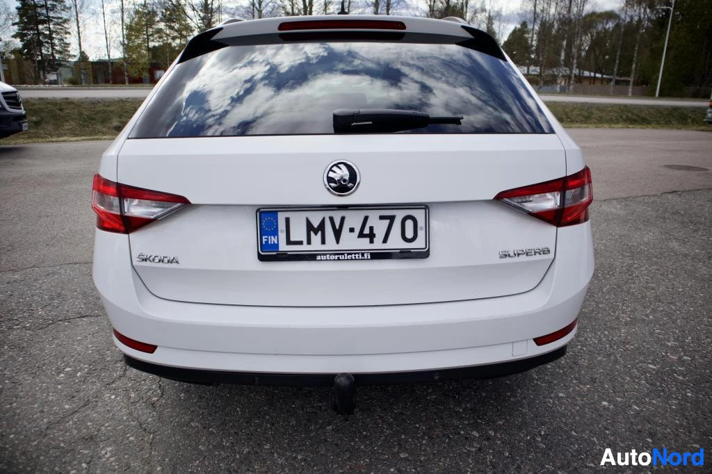 Takaa: Valkoinen Skoda Superb Combi -farmariauton perä, jossa on kilpi '' ja vetokoukku