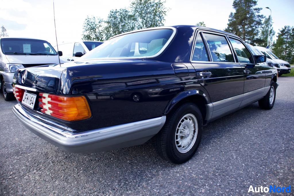 Takaviisto: Tummanpunainen Mercedes-Benz, vasen takakulma kuvattu. Takarekisterikilvessä on teksti "". Autossa on valkoiset kevytmetallivanteet ja krominen puskuri