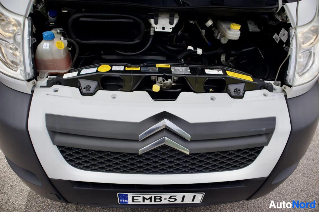 Edestä: Ajoneuvon keula edestä päin kuvattuna, konepelti auki moottoritilan yläosan paljastaen. Keulassa näkyy Citroënin logo ja rekisterikilpi.