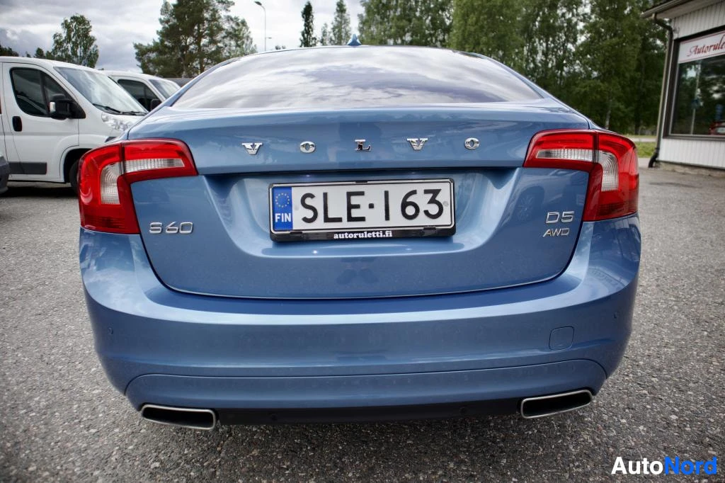 Takaa: Sininen Volvo S60 -henkilöauto kuvattuna suoraan takaa. Autossa on rekisterikilpi "" ja takapuskurissa näkyy kaksi pakoputken ulostuloa. Takaluukussa on