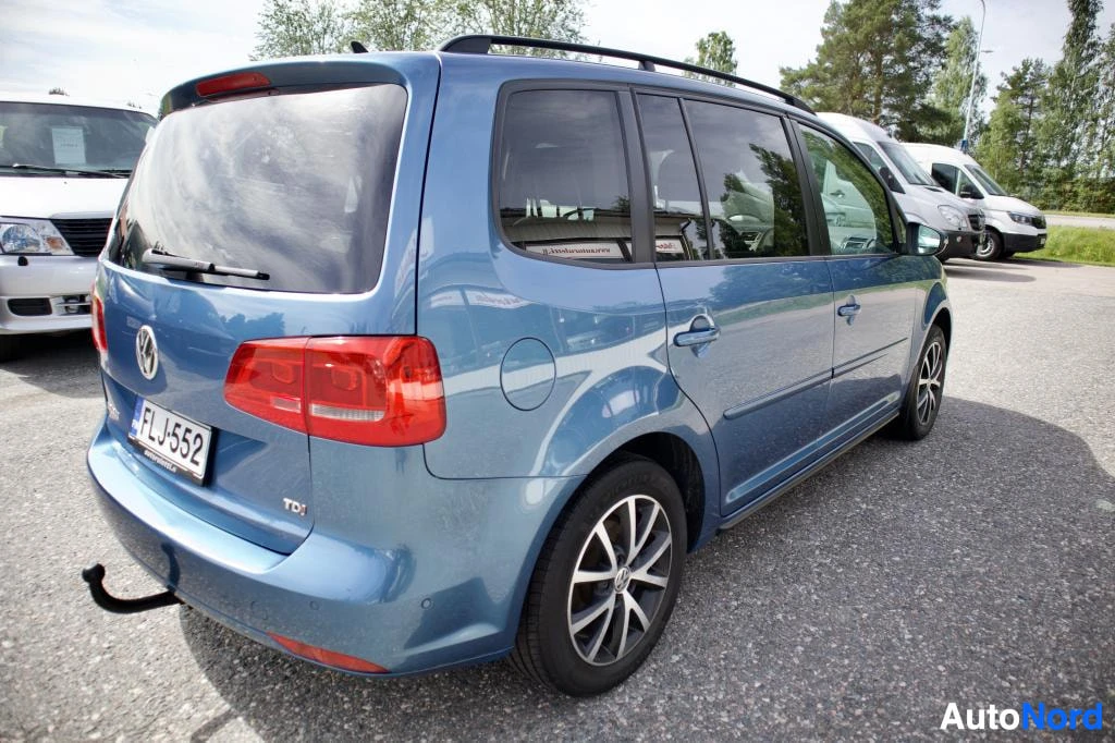 Takaviisto: Sininen henkilöauto oikeasta takaviistosta kuvattuna. Autossa on kattokaiteet ja vetokoukku. Takana näkyy rekisterikilpi ja TDl-merkki. Ajoneuvossa on k