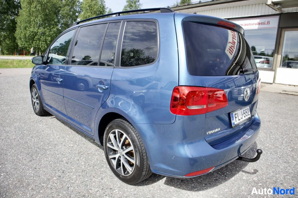 Takaviisto: Sininen henkilöauto vasemmasta takaviistosta kuvattuna. Autossa on kattokaiteet ja vetokoukku. Takana näkyy rekisterikilpi. Ajoneuvossa on kaksiväriset