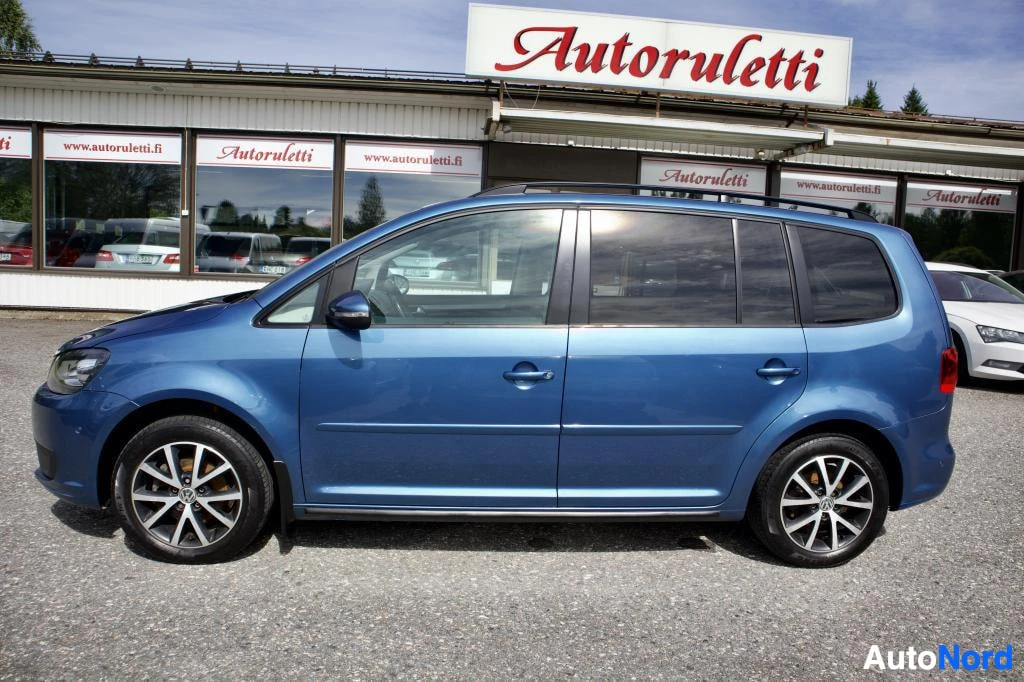 Sivulta: Sininen henkilöauto kuvattuna sivusta. Autossa on kattokaiteet ja kaksiväriset kevytmetallivanteet.