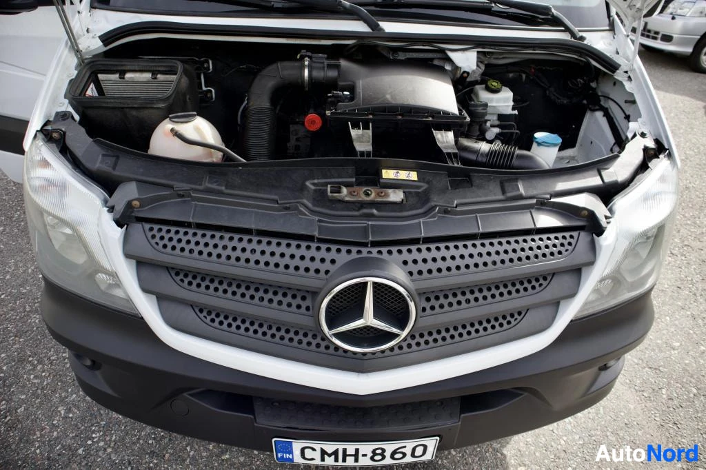 Edestä: Auton etuosa, konepelti auki, paljastaen moottoritilan. Mercedes-Benzin logo näkyy etusäleikössä ja rekisterikilvessä lukee ''