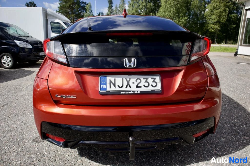 Takaa: Oranssinpunaisen henkilöauton takaosa. Autossa on rekisterikilpi "" ja vetokoukku. Takaluukussa on Honda-logo ja musta paneeli.