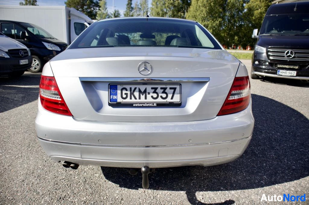 Takaa: Hopeanvärinen Mercedes-Benz C-sarjan sedanin takaosa, rekisterikilpi "" keskellä. Vetokoukku on näkyvissä ja takapuskurissa on pysäköintitutkan antureita