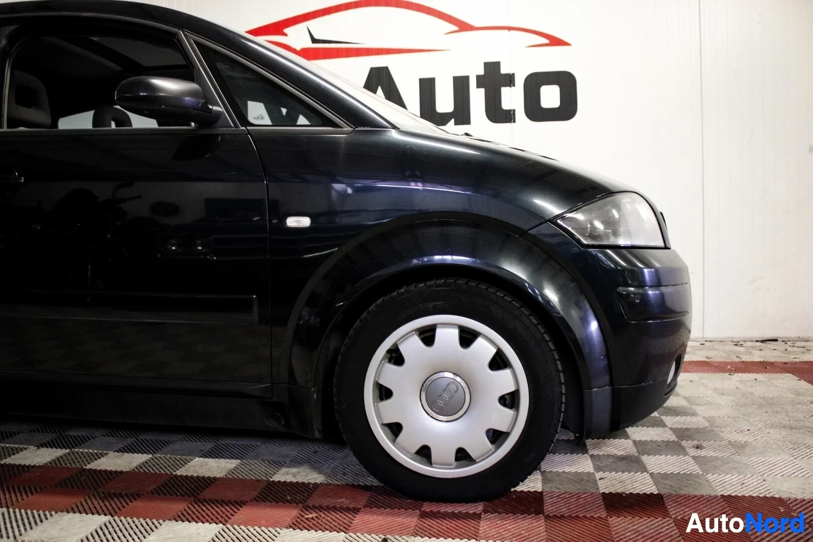 Yksityiskohta: Mustan auton oikea eturengas ja osa keulaa.