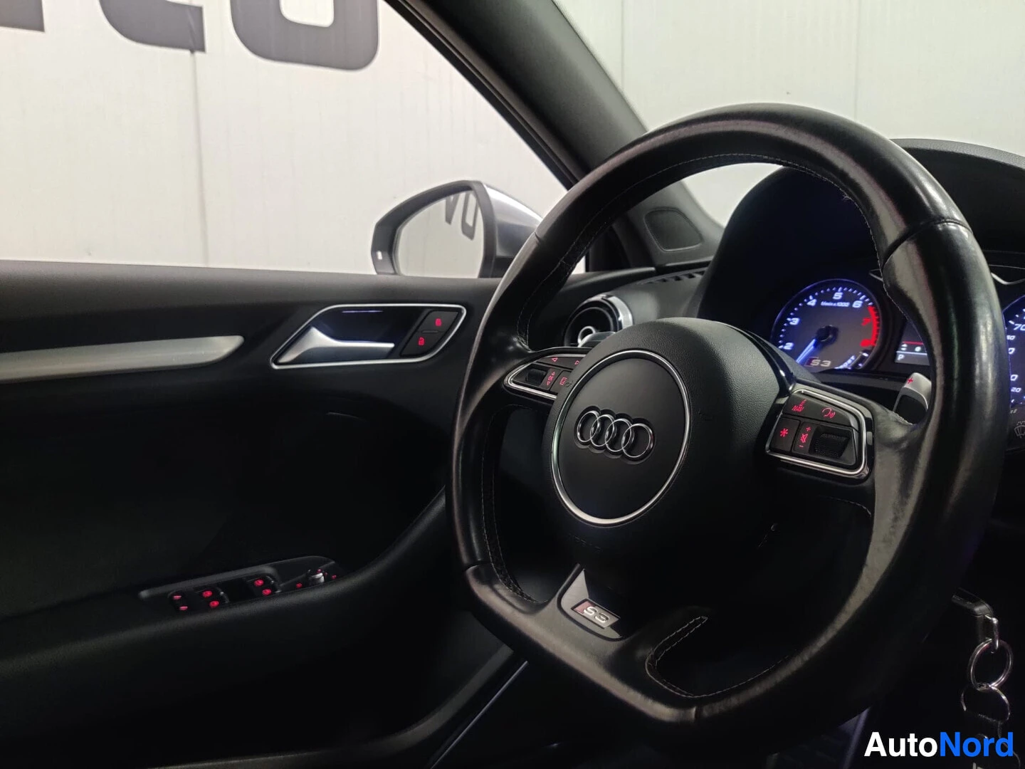 Yksityiskohta: Lähikuva auton ohjauspyörästä ja mittaristosta. Ohjauspyörässä on Audi-logo ja 'S3'-merkki.