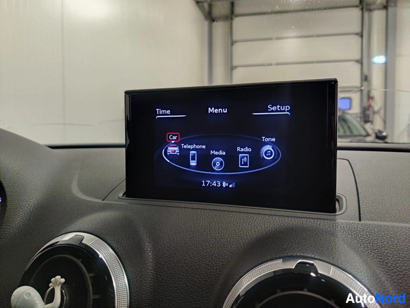 Yksityiskohta: Kuva auton infotainment-järjestelmän näytöstä, jossa näkyy "Car"-valikko ja kellonaika 17:43. Näytöllä on ikonit puhelimelle, medialle ja radiolle.