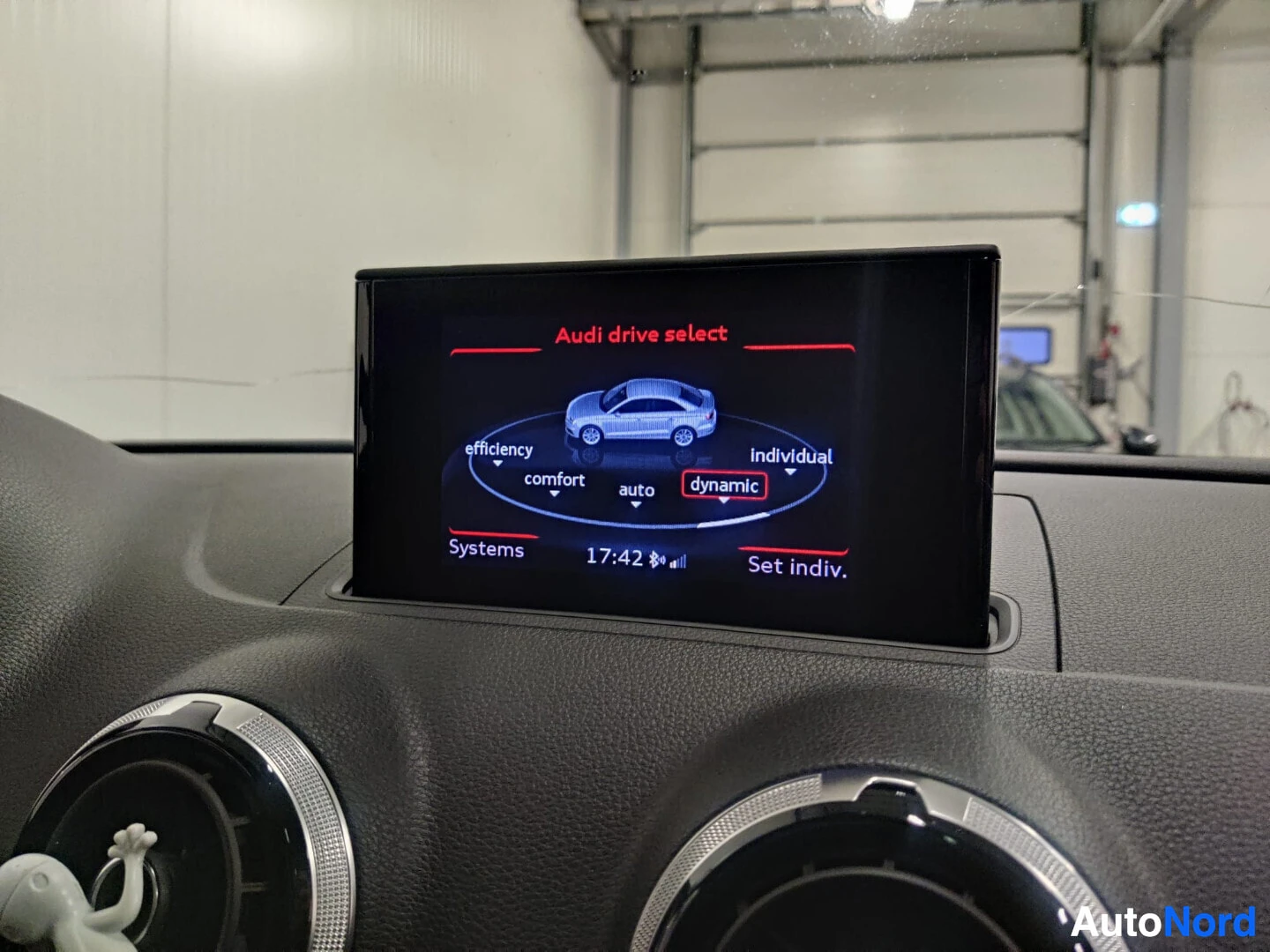 Yksityiskohta: Kuva auton infotainment-järjestelmän näytöstä, jossa näkyy "Audi drive select" -valikko ja valittuna "dynamic"-tila. Myös "efficiency", "comfort", "auto" ja "in
