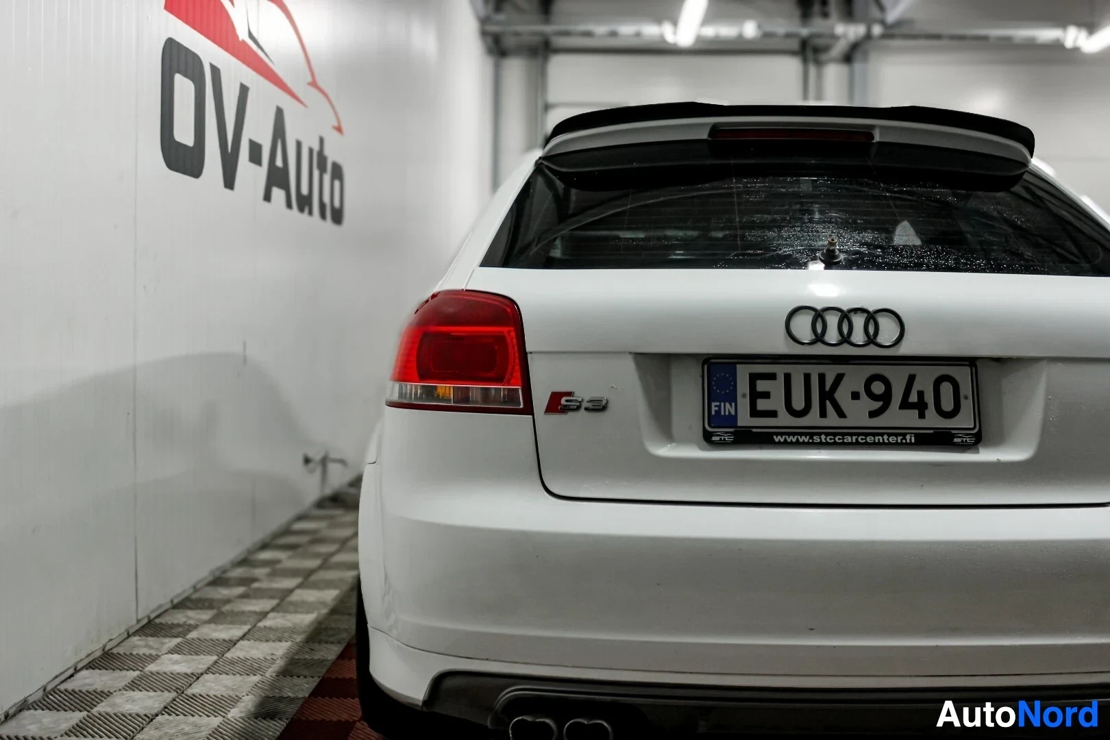 Takaa: Valkoisen kaksiovisen hatchback-auton takaosa, jossa rekisterikilpi. Takavalot ja Audi-logo ovat myös näkyvissä. Autossa on takaspoileri ja kaksi pakopu
