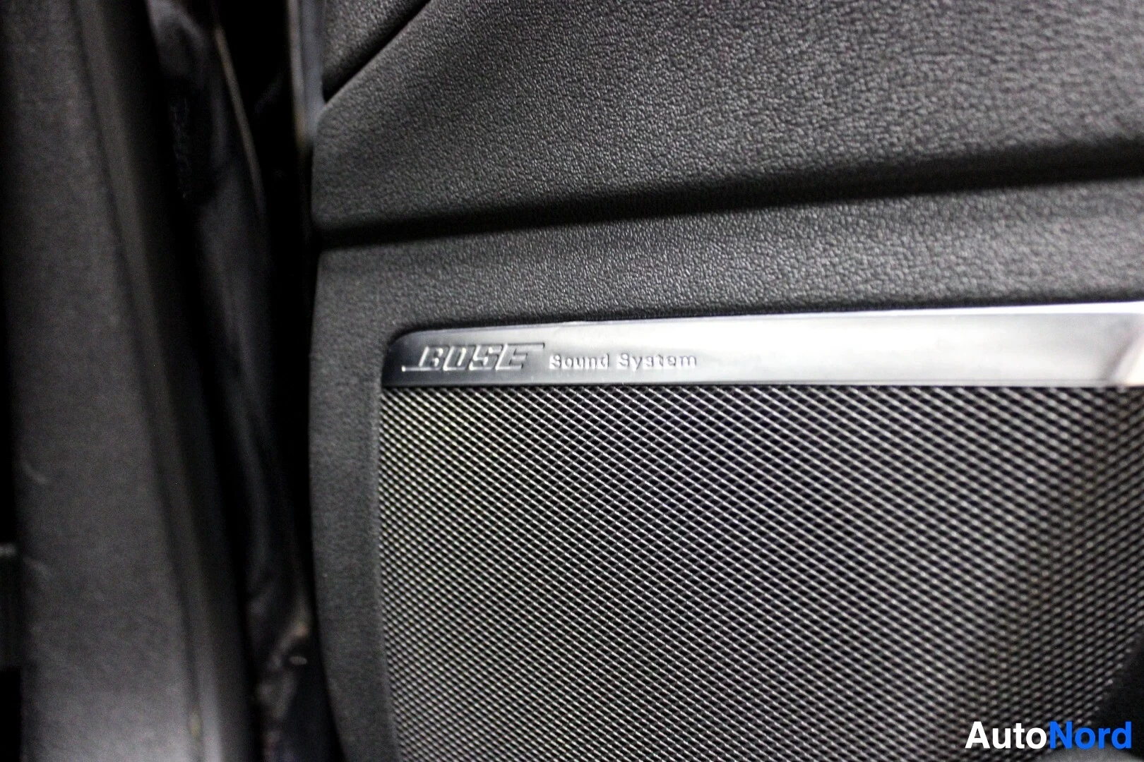 Yksityiskohta: Lähikuva oven kaiuttimesta, jossa on "BOSE Sound System" -merkintä kiiltävässä kehyksessä kaiuttimen yläpuolella.