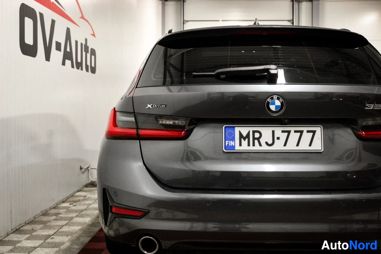 Takaa: Auton takaosa, jossa näkyy takaluukku, takavalot ja rekisterikilpi. Takaluukun yläosassa on pyyhin ja BMW-logo. xDrive-merkki näkyy vasemmalla puolella
