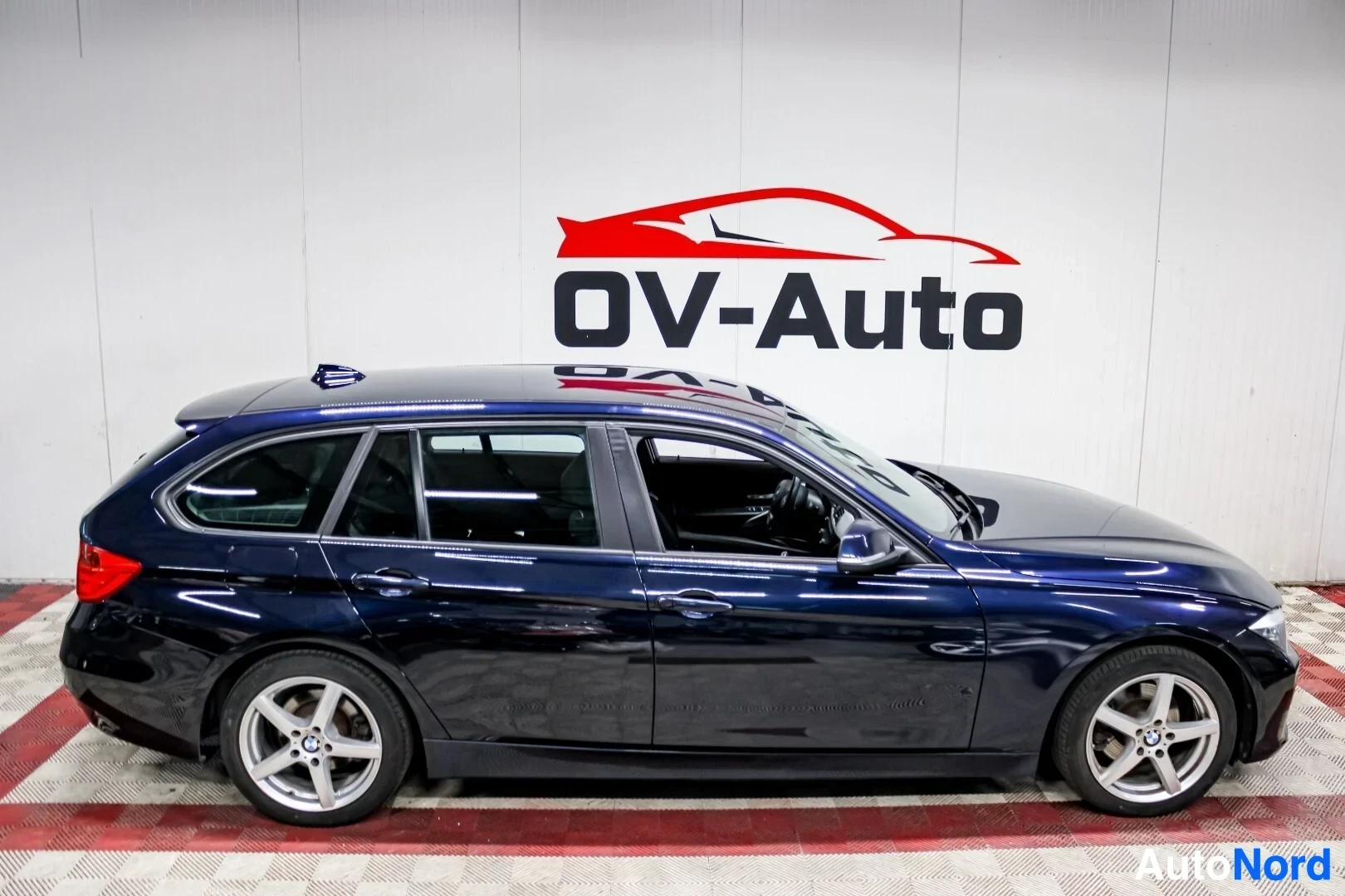 Sivulta: Sininen farmariauto vasemmalta sivulta kuvattuna. Autossa näkyy kattokiskot ja kevytmetallivanteet.