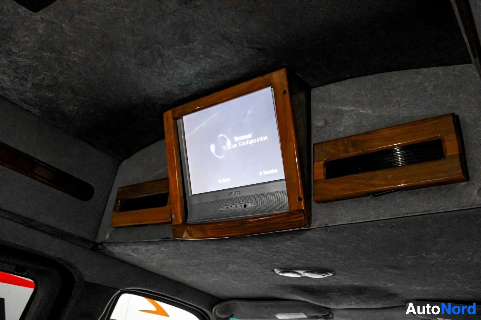 Yksityiskohta: Kuva auton katonrajaan asennetusta televisiosta. Televisio on sijoitettu puiseen kehykseen ja sen näytöllä näkyy tekstiä "Browser System Configuration".