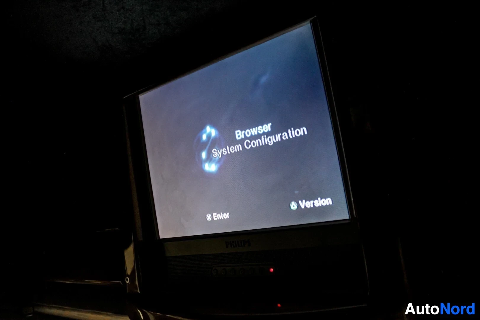 Yksityiskohta: Lähikuva televisiosta, joka näyttää käynnistyvän PlayStation 2 -konsolin käyttöliittymän, jossa lukee "Browser System Configuration" ja alareunassa "Enter" ja "
