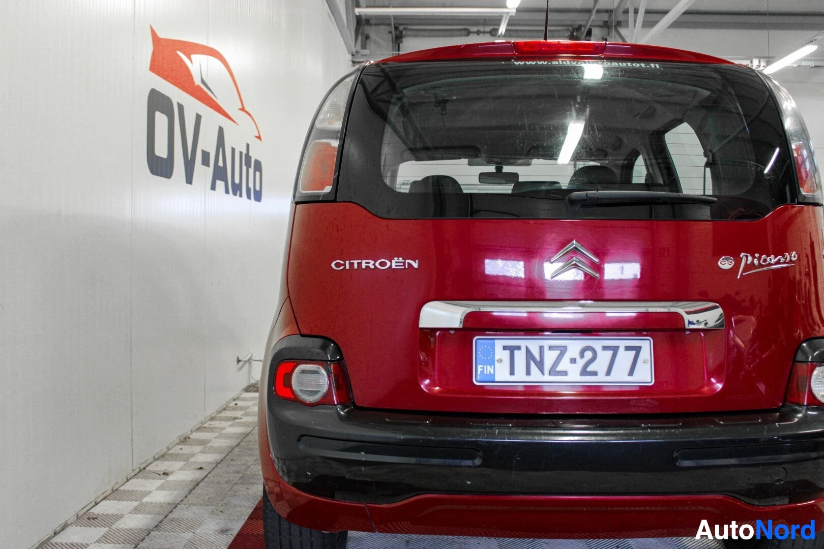 Takaa: Punainen henkilöauto takaa kuvattuna, rekisterikilpi "" ja Citroën-logo takaluukussa. Takavalot ja takapuskuri näkyvissä