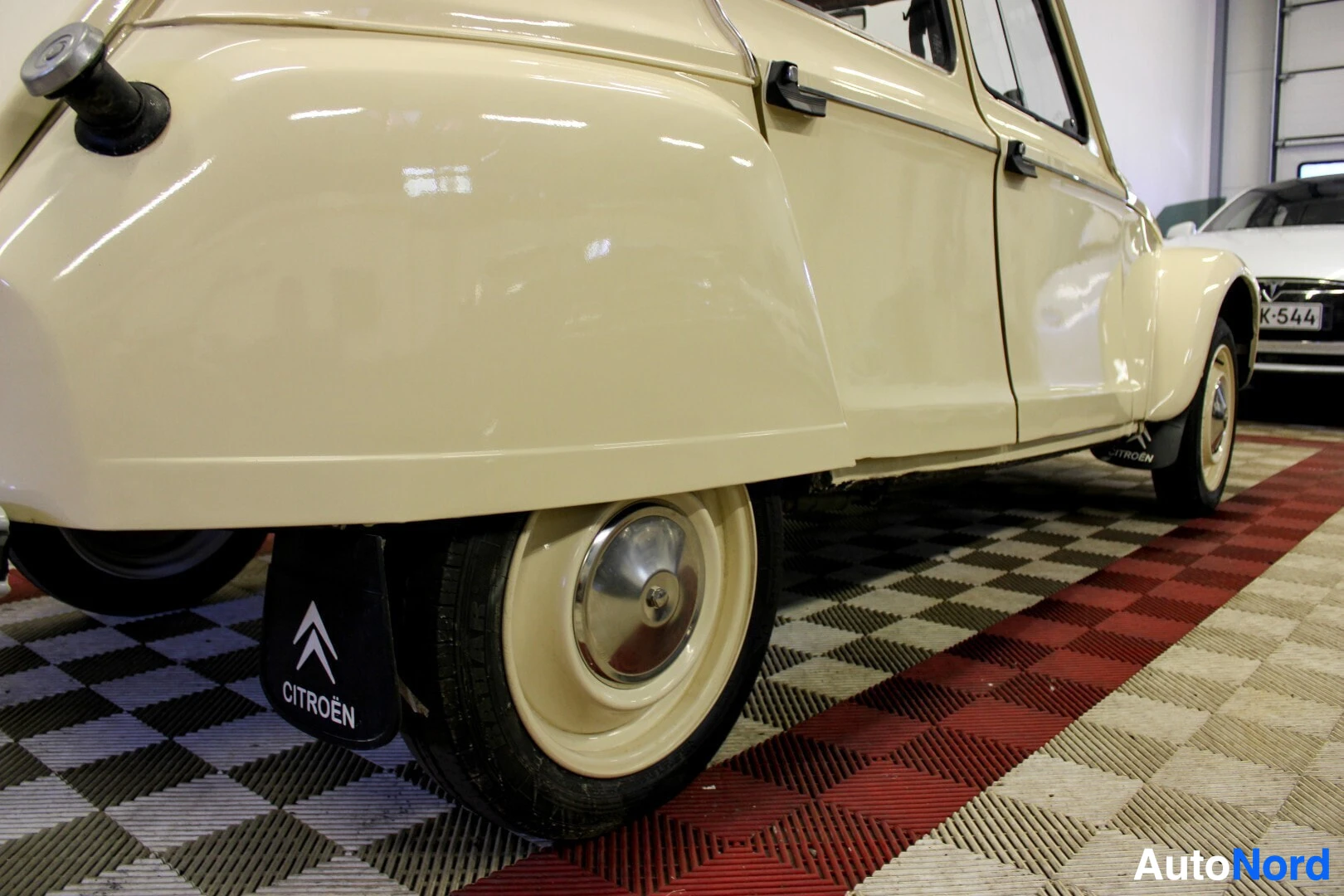 Takaviisto: Auton takavasen kylki näkyy matalasta kuvakulmasta. Takapyörässä on pölykapseli. Takalokasuojassa on musta roiskeläppä, jossa on "CITROËN"-logo ja -teksti.