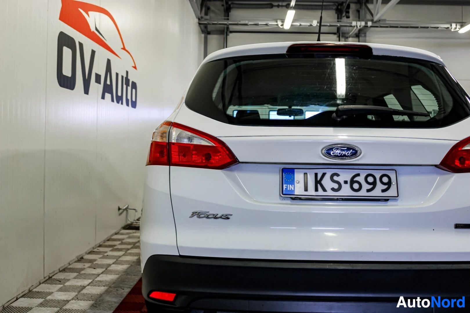 Takaa: Valkoisen farmariauton perä. Autossa on Ford-logo ja Focus-merkki takaluukussa. Rekisterikilpi on asennettu