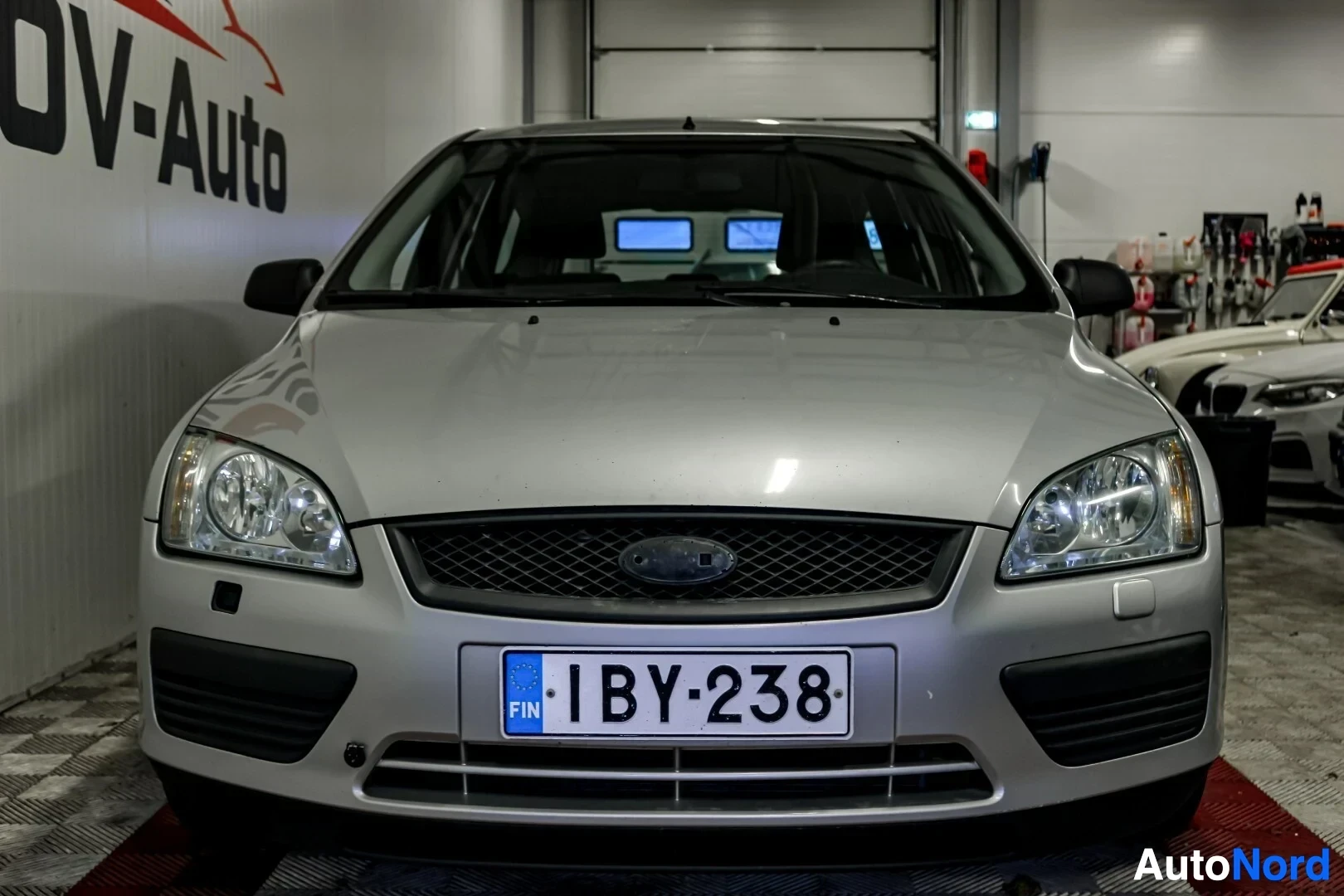 Edestä: Ford Focus farmariauto edestä päin kuvattuna. Auton hopeanvärinen konepelti ja etupuskuri näkyvät selvästi. Rekisterikilpi on sijoitettu etupuskurin kes