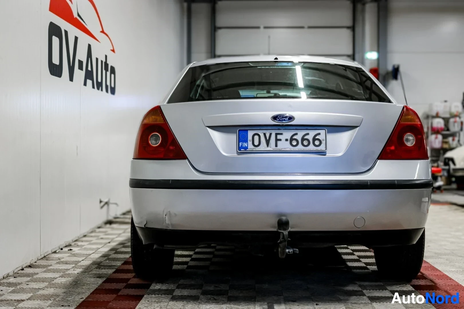 Takaa: Hopeanvärinen Ford Mondeo henkilöauto kuvattuna suoraan takaa. Vetokoukku, kaksi peruutusanturia ja rekisterikilpi ovat näkyvissä
