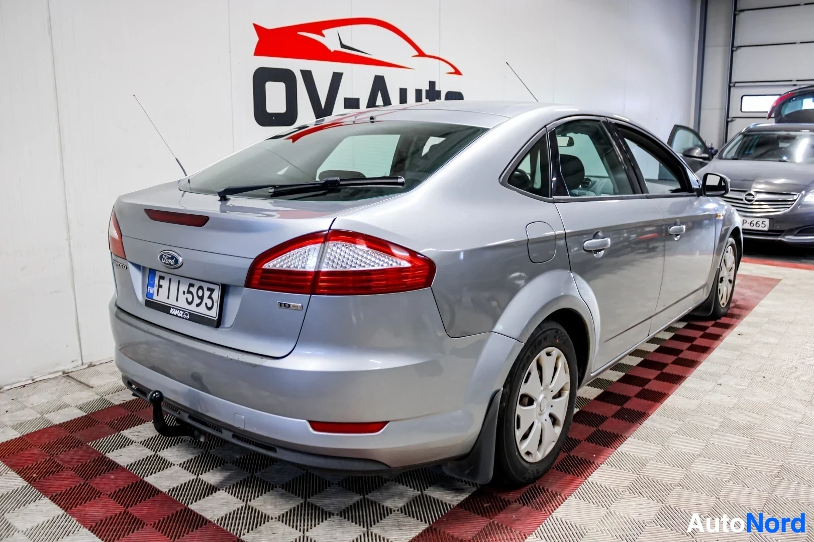Takaviisto: Hopeanharmaa Ford Mondeo, jossa on vetokoukku, on pysäköity sisätiloihin vasemman takakulman näkymässä, auton takaosa ja oikea kylki näkyvissä. Rekisterikilpi o