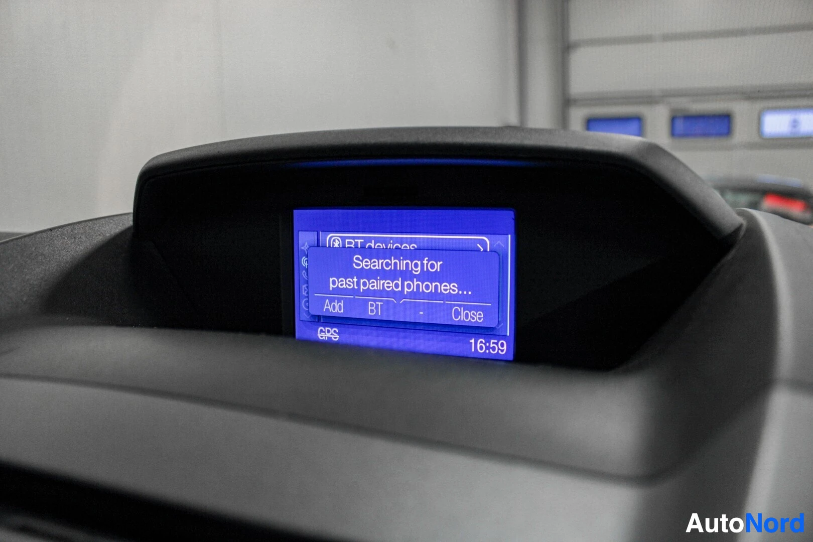 Yksityiskohta: Lähikuva auton näytöstä, jossa lukee englanniksi "Searching for past paired phones..." ja valinnat "Add", "BT" ja "Close". Näytön alareunassa lukee "GPS" ja kel