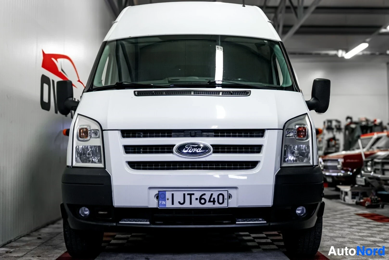 Edestä: Ford Transit -pakettiauton etuosa. Autossa on Ford-logo jäähdyttimen säleikössä ja rekisterikilpi