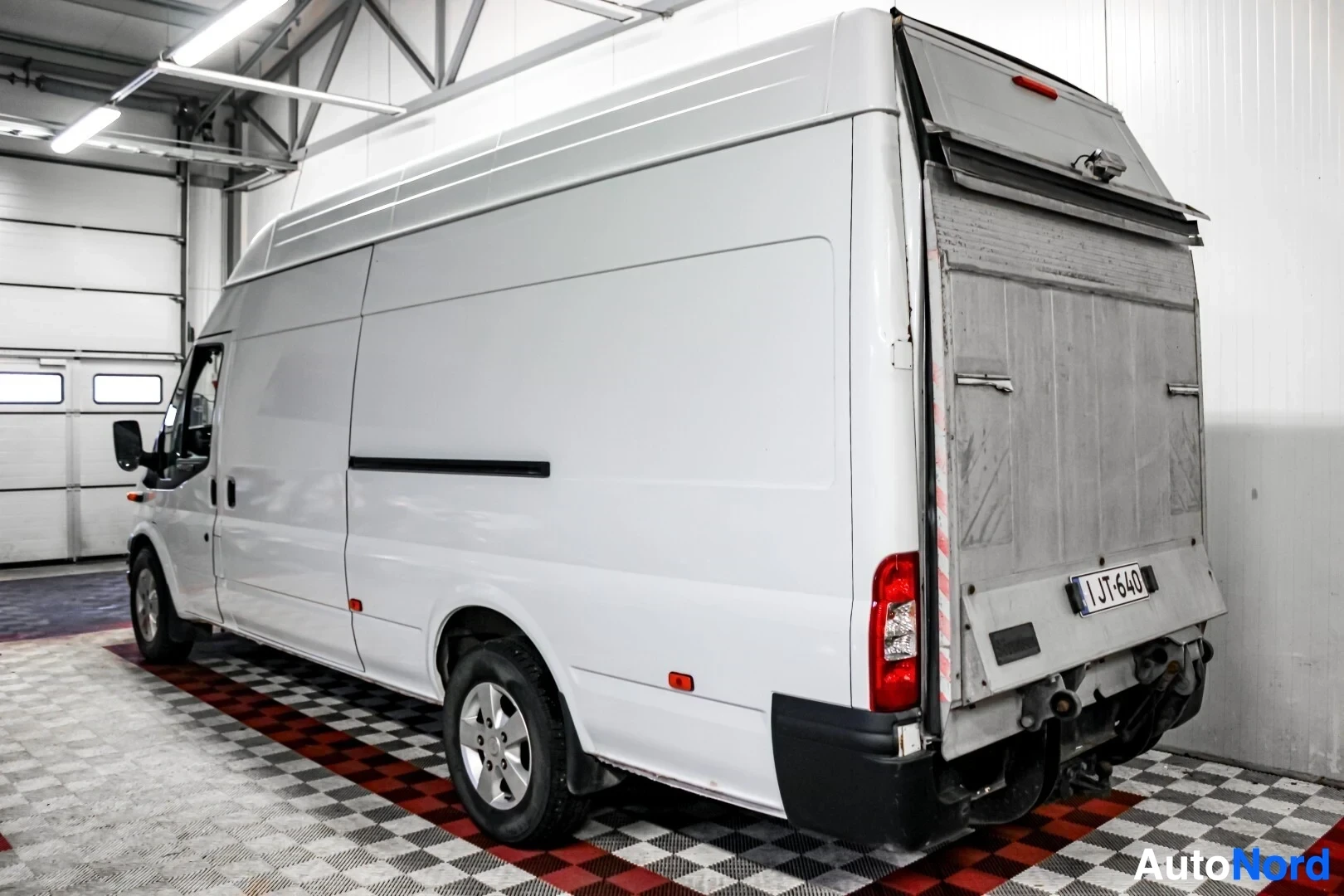 Takaviisto: Ford Transit -pakettiauton takaosa ja oikea kylki kuvattuna valaistussa hallissa. Auton takaluukku on auki ja auton oikeanpuoleinen takaovi on liukuovi.