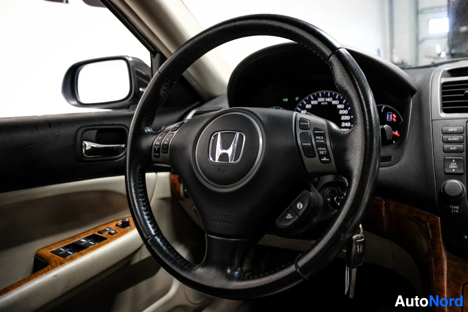 Yksityiskohta: Yksityiskohta ohjauspyörästä, jossa näkyy Honda-logo ja "CRUISE CONTROL" -painikkeet oikeassa puolassa. Vasemmalla puolella on multimediaohjaimet. Auton avaimet