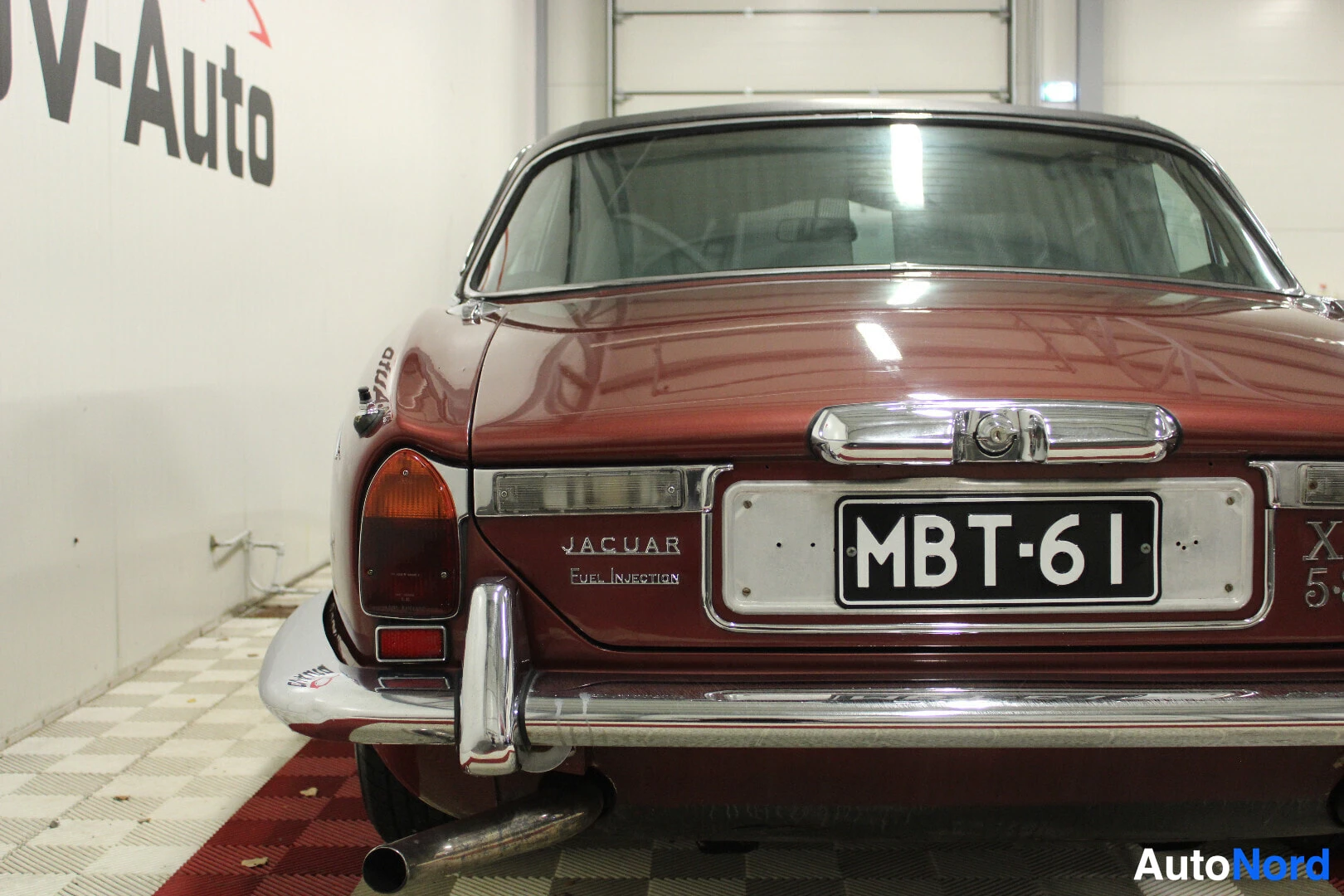 Takaa: Punaisen henkilöauton takaosa, jossa näkyy pakoputki, rekisterikilpi ja "JAGUAR Fuel Injection" -merkintä.
