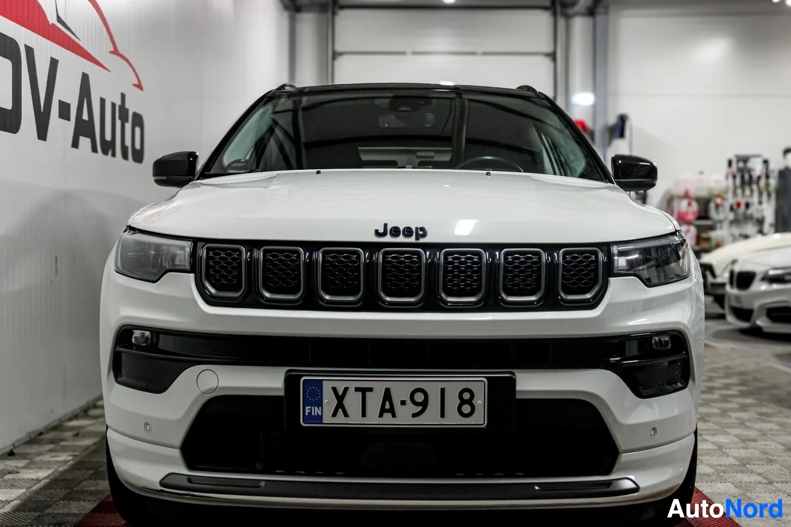 Edestä: Valkoinen Jeep Compass edestä kuvattuna. Auton etupuskurissa on rekisterikilpi