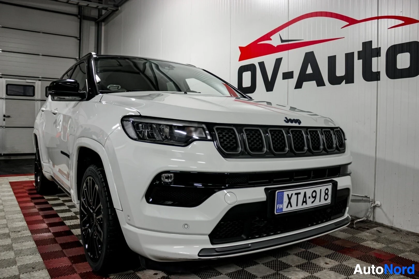 Etuviisto, nokka oikealle: Valkoinen Jeep Compass vasemmalta edestä kuvattuna. Autossa on musta katto ja mustat vanteet.