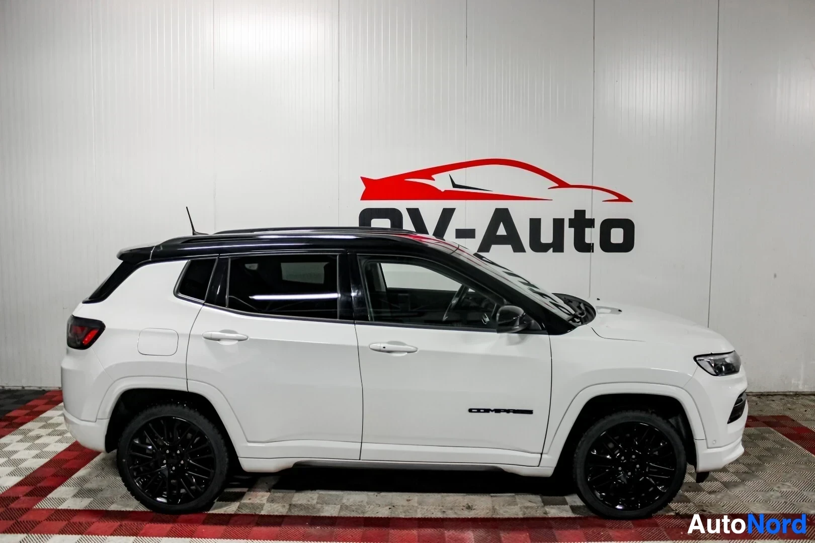 Sivulta: Valkoisen Jeep Compassin vasen kylki kuvattuna suoraan sivusta sisätiloissa.