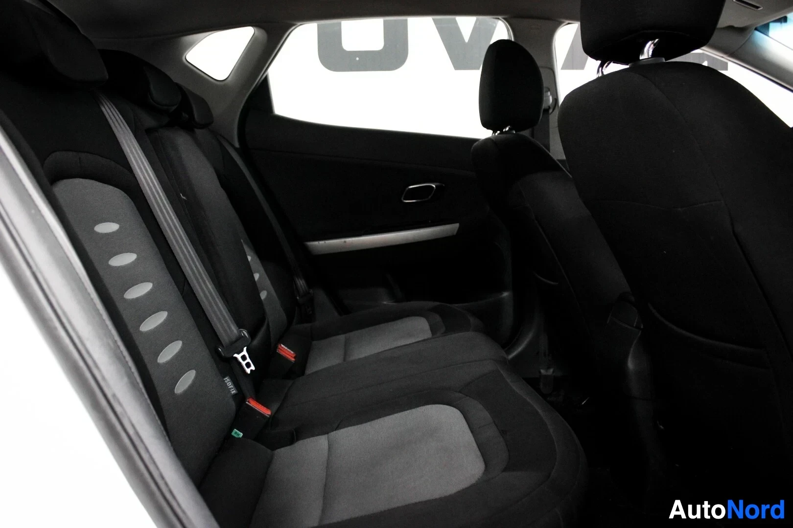 Takaistuimet: Kuvassa näkyy auton takaistuinrivi, jossa on kangasverhoillut istuimet ja turvavyöt. Vasemmanpuoleisen istuimen selkänojassa on ISOFIX-merkintä. Ovi on auki.