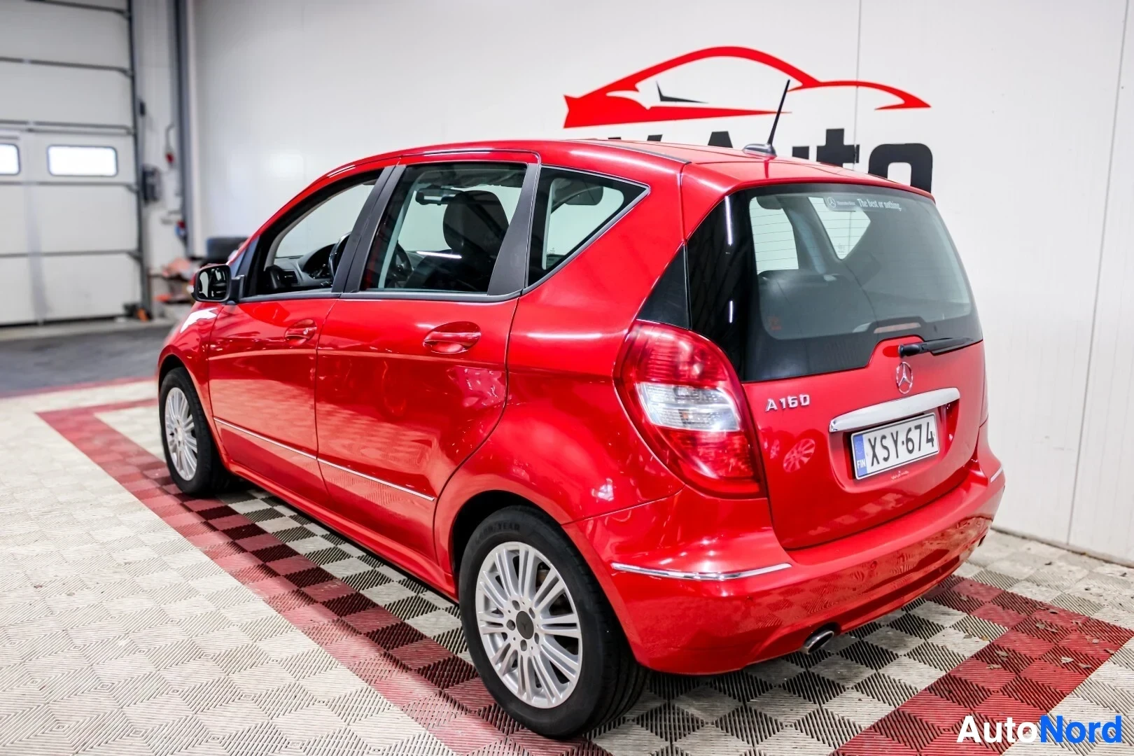 Takaviisto: Punainen henkilöauto on kuvattu takaviistosta. Auton takaosa ja vasen kylki ovat näkyvissä. Takaluukussa on mallimerkintä "A 160". Rekisterikilpi on ""