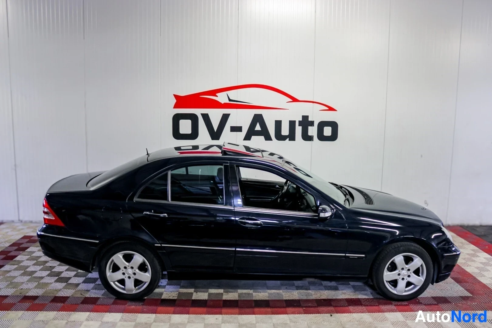 Sivulta: Musta henkilöauto kuvattuna sivusta, vasemmalta. Autossa on valkoiset kevytmetallivanteet ja avoin kattoluukku.