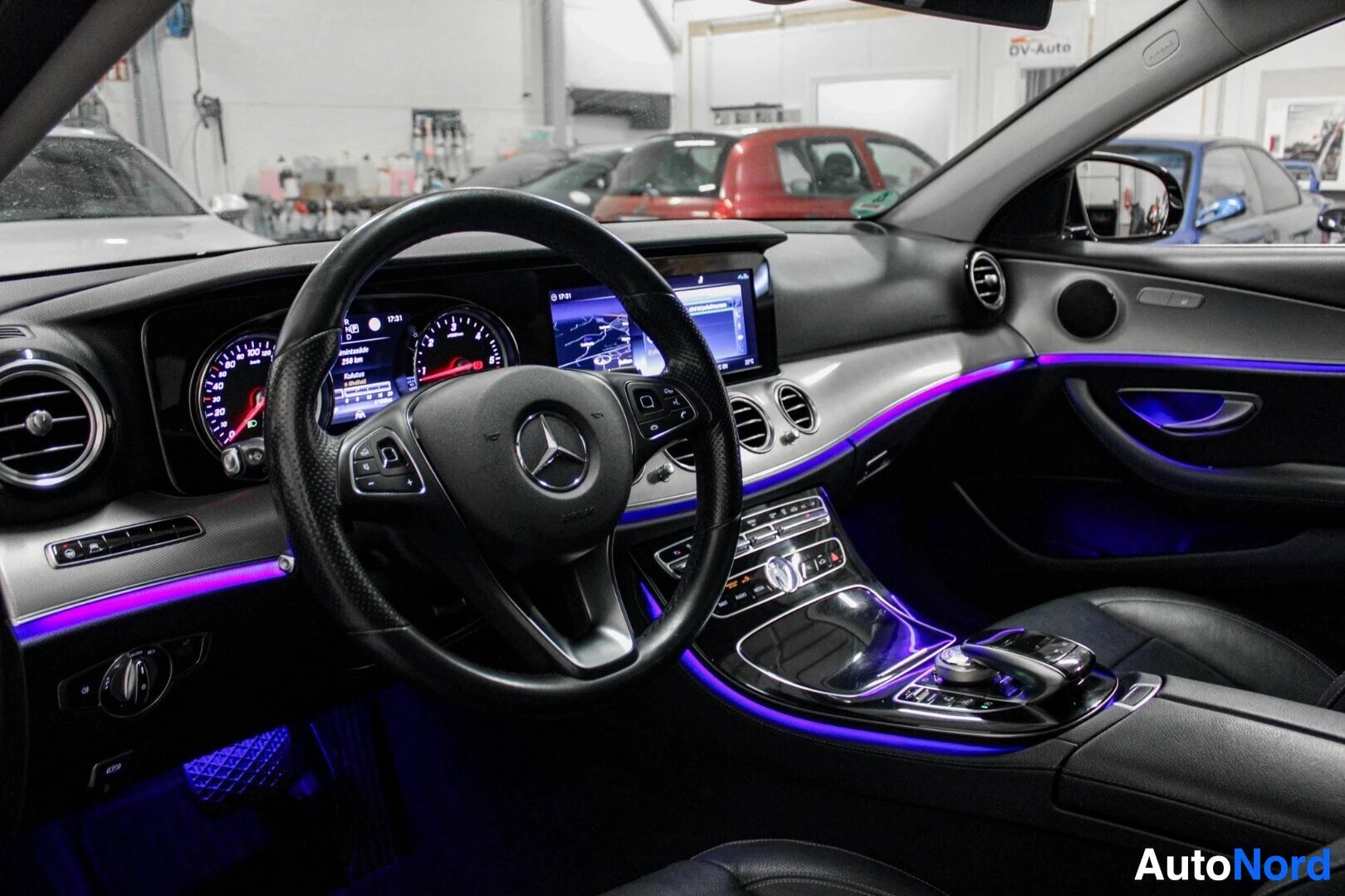 Ohjaamo: Auton sisätilat kuvattuna kuljettajan puolelta. Näkyvissä on ohjauspyörä, jossa on Mercedes-Benz-logo, digitaalinen mittaristo ja keskikonsolin näyttö. Sisätila