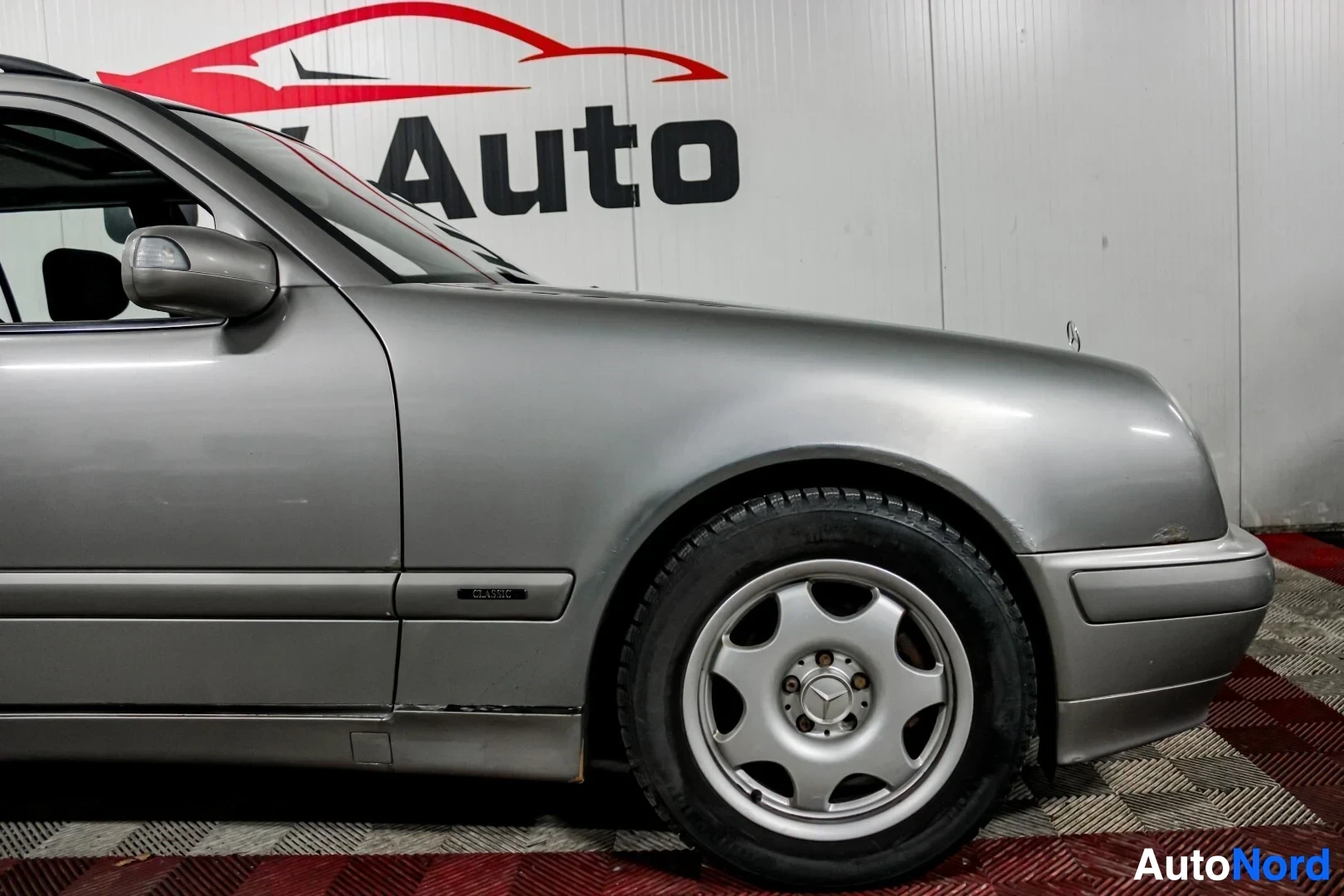 Sivulta: Auton harmaa etulokasuoja ja etupyörä, jossa on kevytmetallivanne. Kyljessä teksti "CLASSIC".