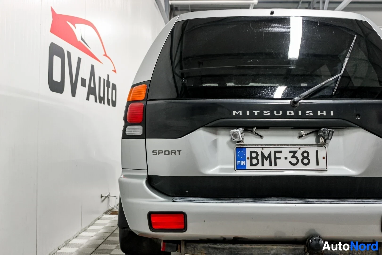 Takaa: Auton takaosa lähikuvassa. Takarekisterikilvessä on teksti "". Takaluukussa on Mitsubishin logo ja "SPORT"-teksti