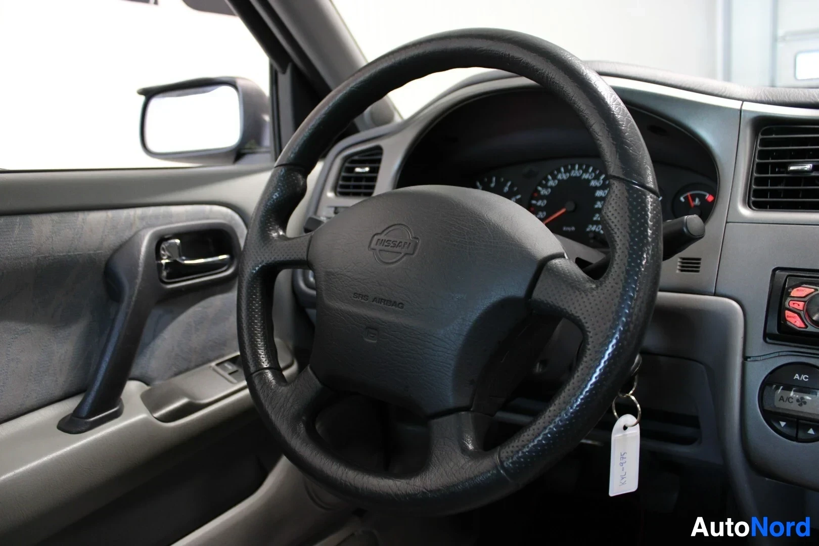Yksityiskohta: Kuljettajan puoleinen ovi ja ohjauspyörä, jossa on Nissan-logo ja teksti "SRS AIRBAG".