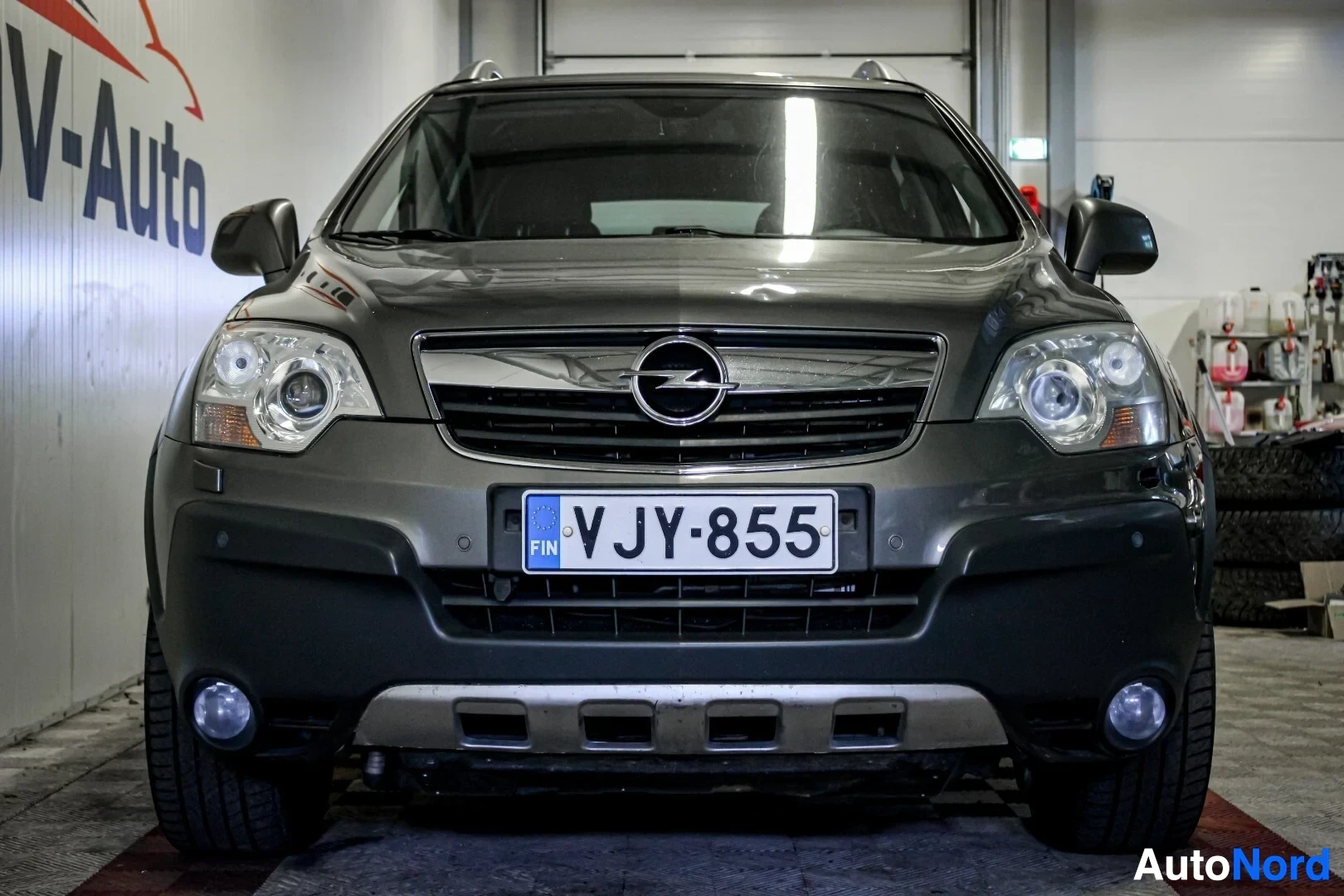 Edestä: Tummanharmaa henkilöauto edestä kuvattuna. Autossa on etupuskurissa pysäköintitutkan sensorit ja sumuvalot.