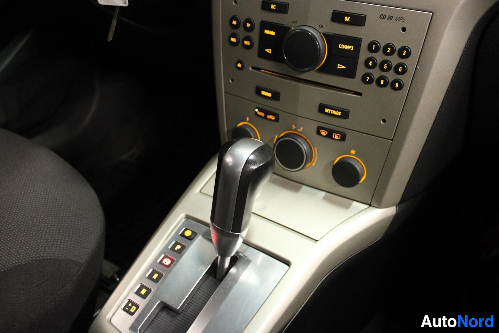 Ohjaamo: Lähikuva auton keskikonsolista, jossa näkyy automaattivaihteisto, CD 30 MP3 -radio, ja ilmastoinnin säätimet.