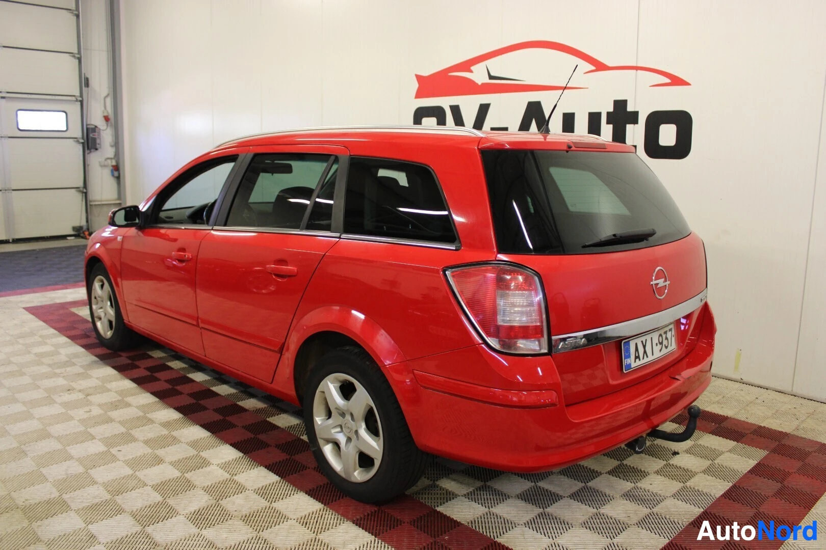 Takaviisto: Punainen henkilöauto takaoikealta viistosti kuvattuna. Takaluukun alareunassa on vetokoukku.