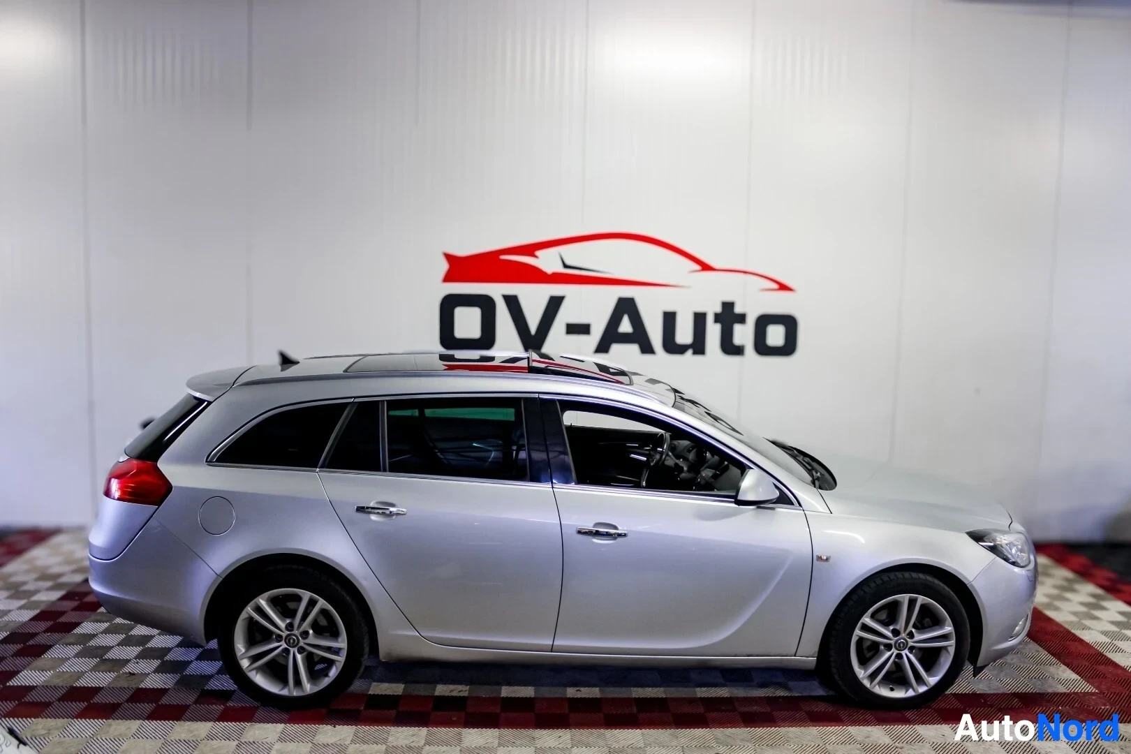 Sivulta: Hopeanvärinen farmariauto vasemmalta sivulta kuvattuna. Autossa on kattokaiteet ja kevytmetallivanteet.