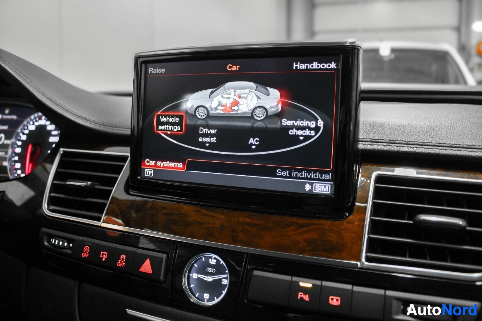 Ohjaamo: Auton kojelaudan keskikonsolin näyttö, jossa näkyy auton kuva ja valikkoja kuten "Vehicle settings", "Driver assist", "AC" ja "Servicing & checks". Näytön alla