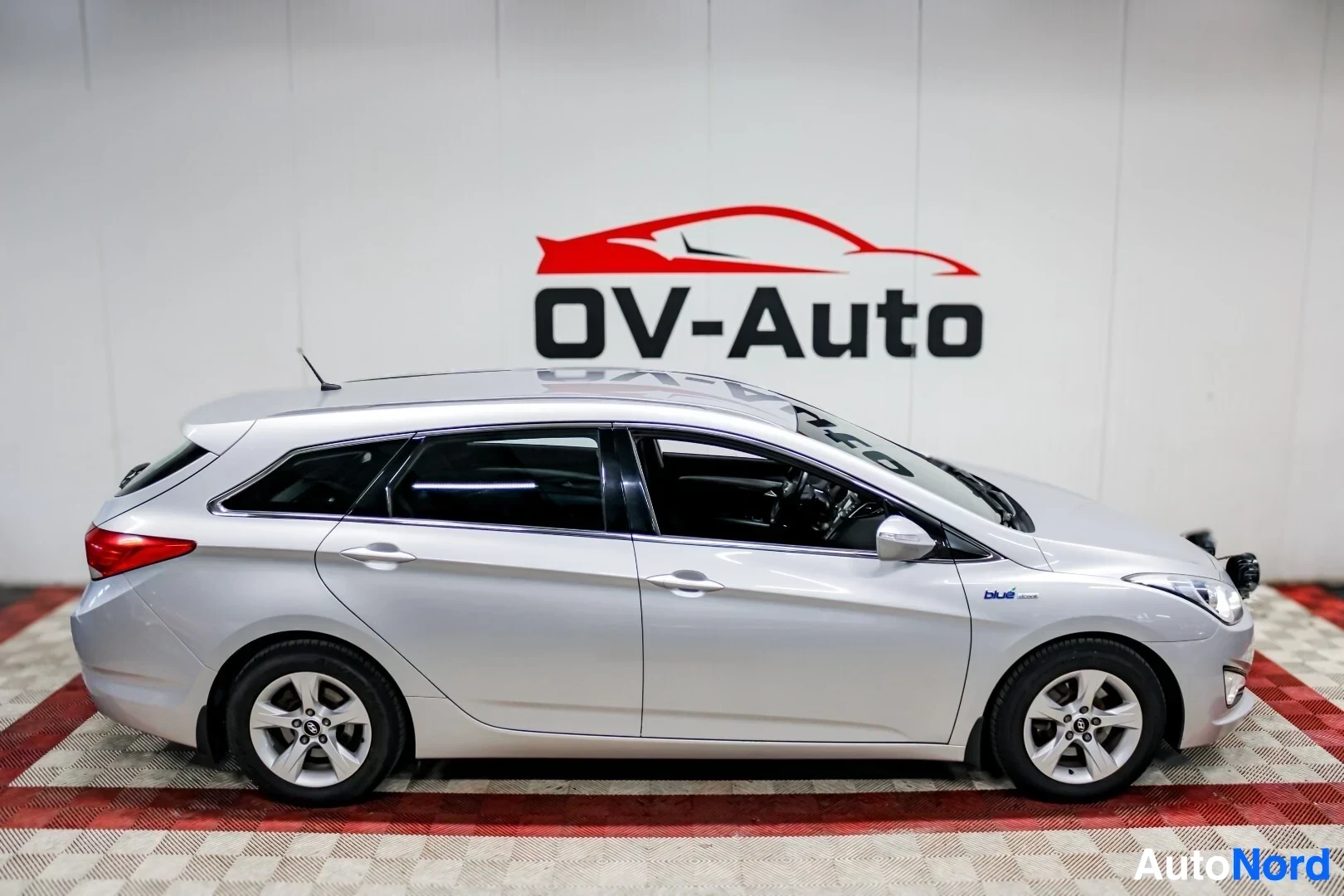 Sivulta: Hopeanvärinen farmariauto sivulta kuvattuna. Autossa on kattokiskot ja kevytmetallivanteet.