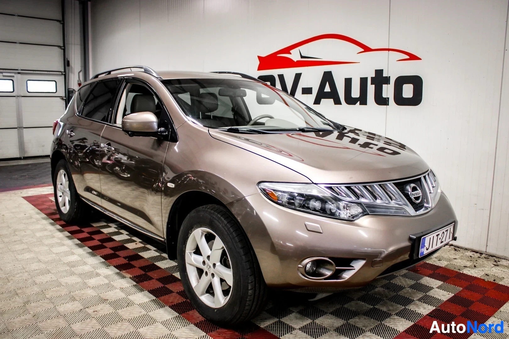 Etuviisto, nokka oikealle: Nissan Murano ruskeassa metallivärissä, kolmen neljäsosan etunäkymä vasemmalta, hopeavanteet ja kattokaiteet.