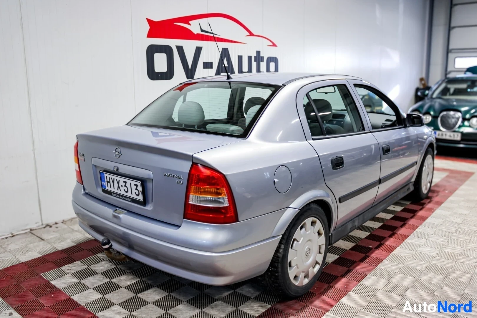 Takaviisto: Hopeanvärinen Opel Astra, jossa on vetokoukku, kuvattuna takaviistosta sisätiloissa.